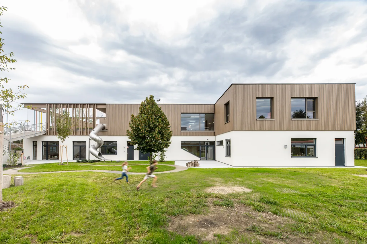 Kindergarten Leopoldsdorf: Aufstockung in Massivholzbauweise mit Holzfassade und Spielwiese