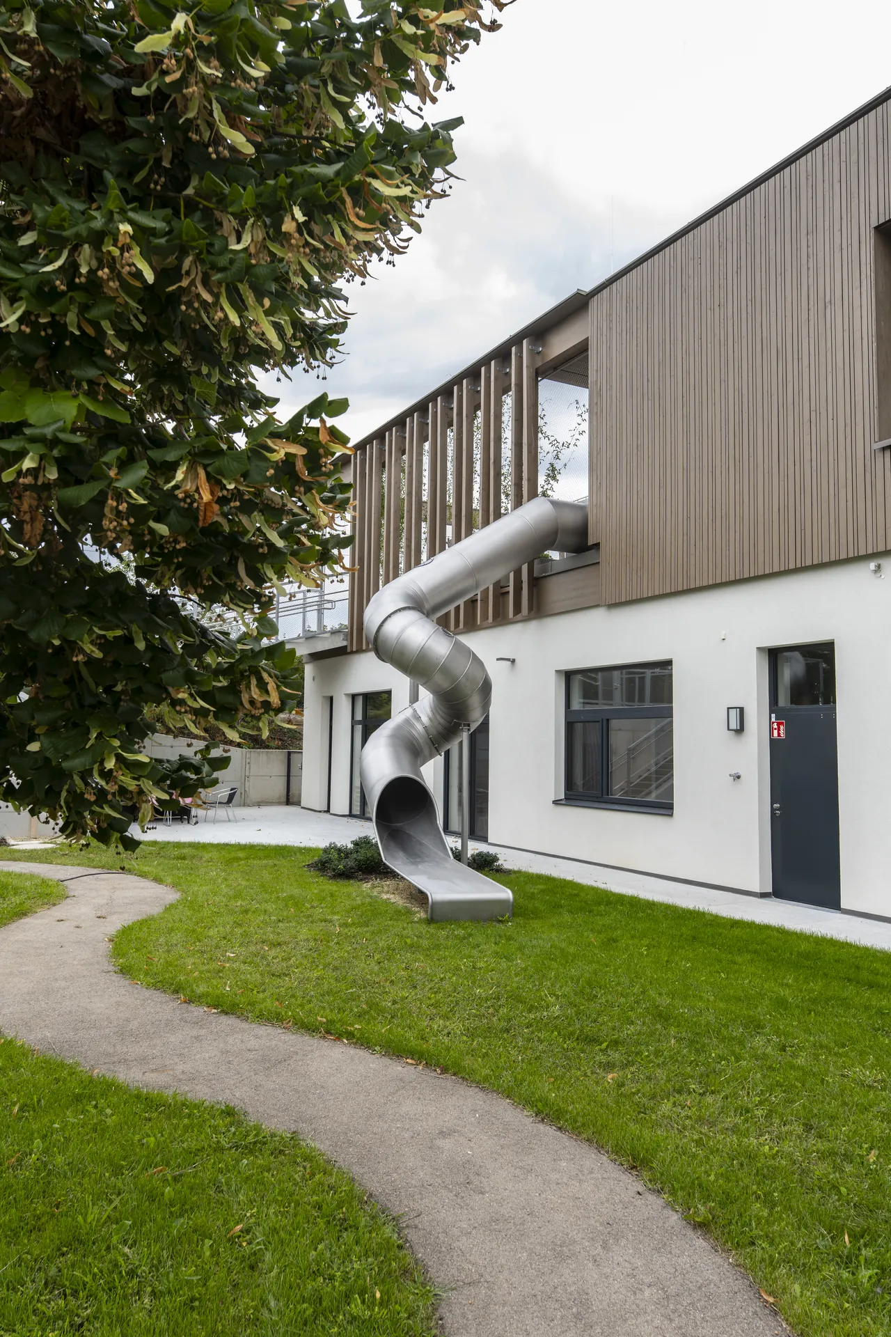Gartenseite mit Rutsche und Holzfassade der Aufstockung