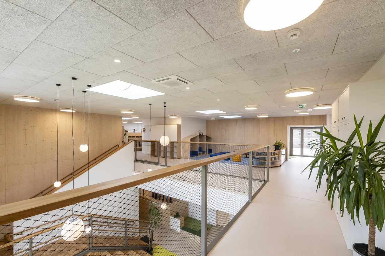 Foyer mit Galerie, Holztreppe und Pflanzen im Obergeschoss