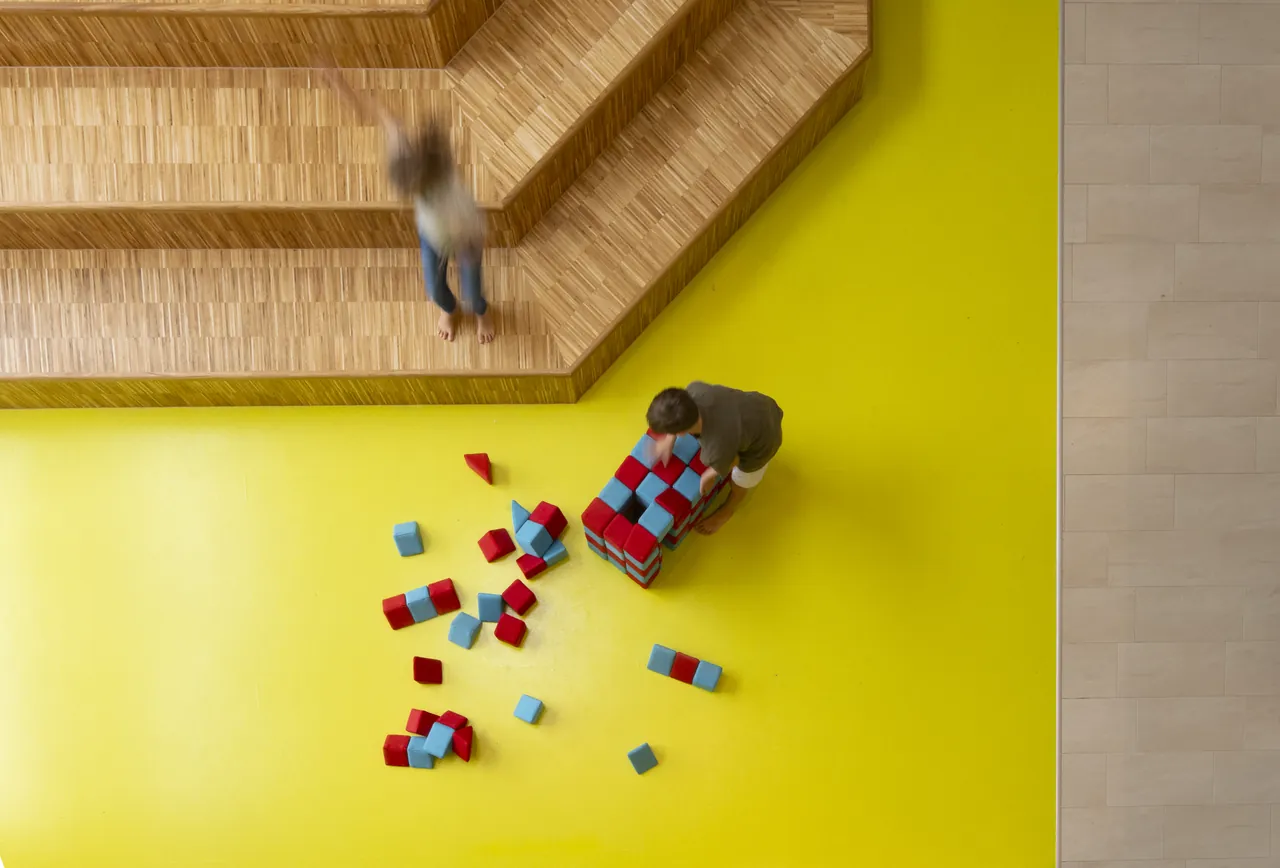 Luftaufnahme eines Spielbereichs mit buntem Spielzeug auf gelbem Boden