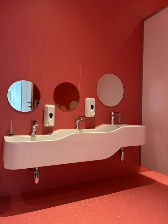 Sanitärraum in Rot mit runden Spiegeln